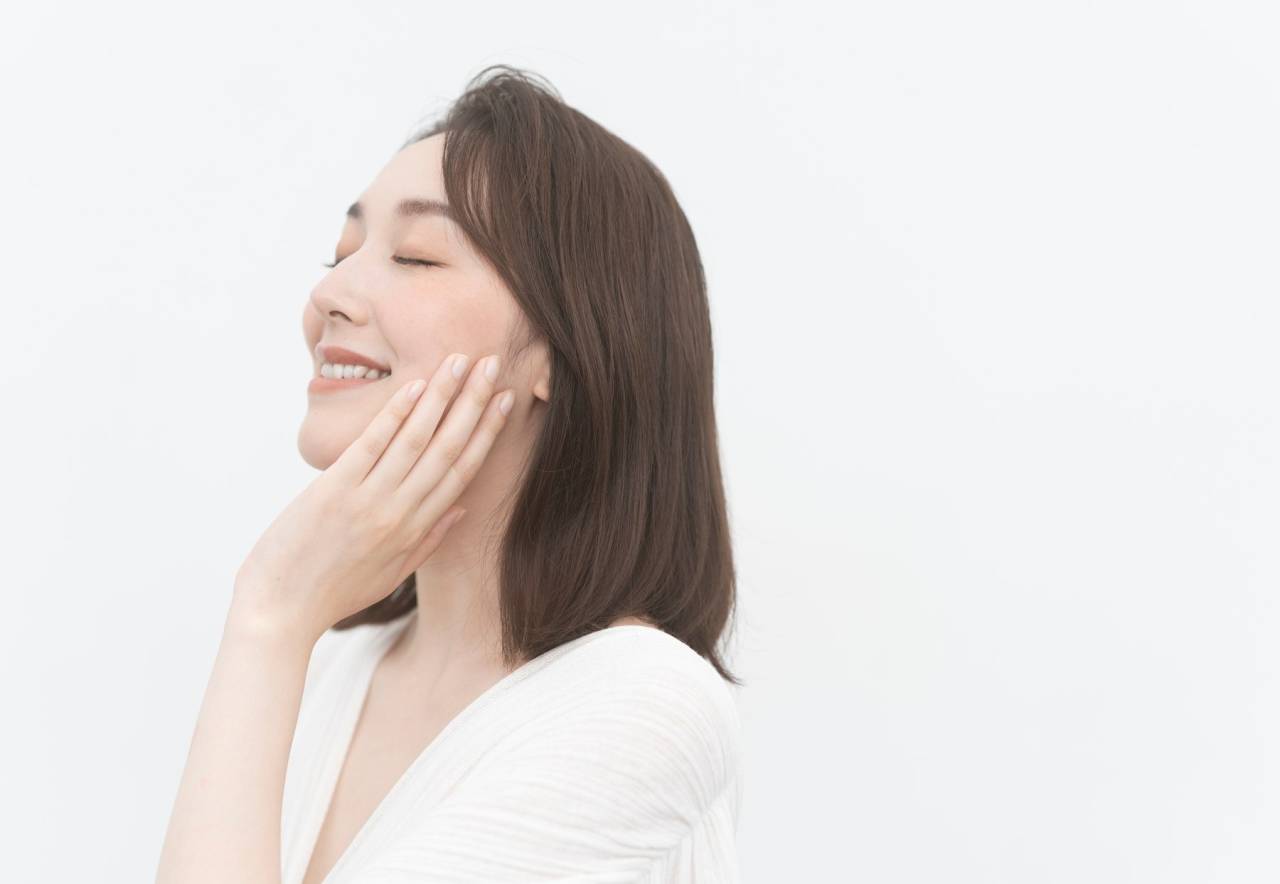 頬に手を添える女性モデル。フェイシャルケアのイメージ